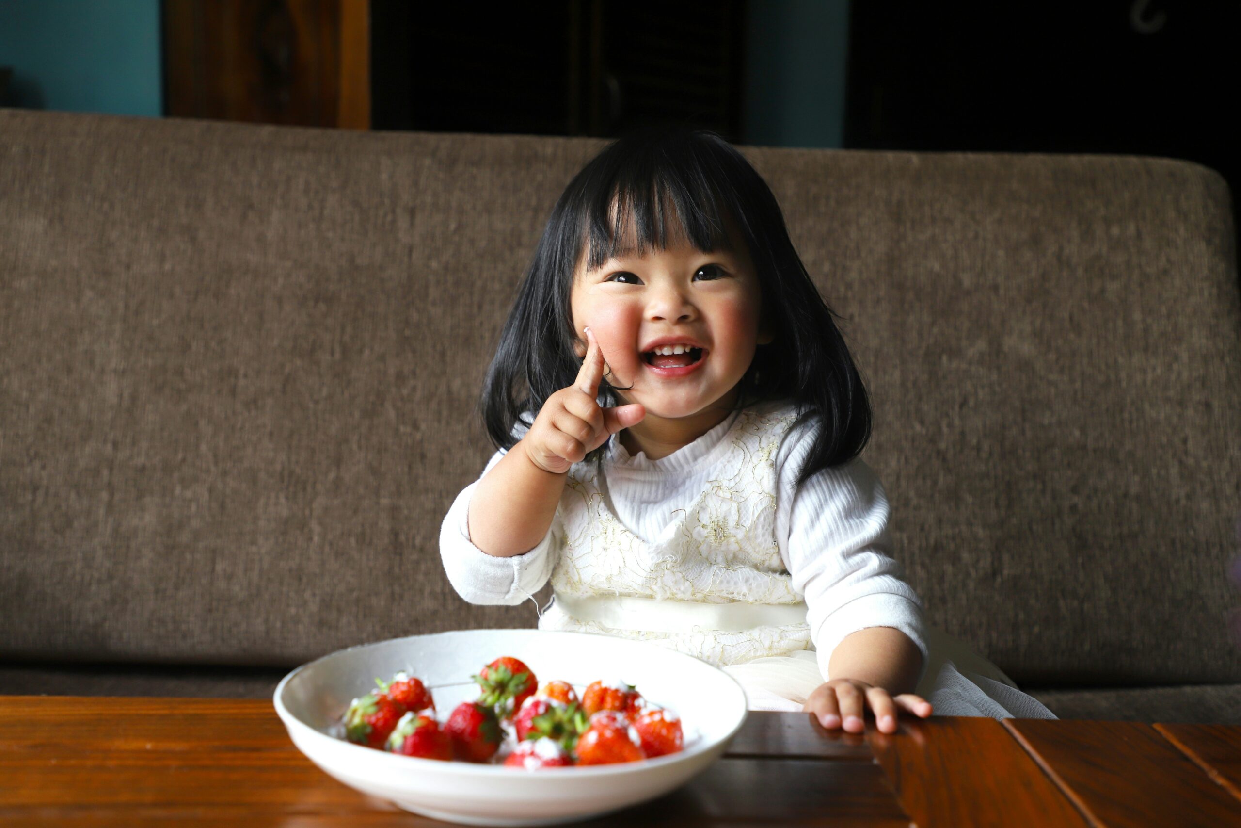 toddler girl, happily eating berries and cream at a restaurant